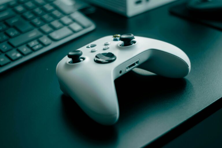 Close-up of a white game controller on a sleek desk, highlighting technology and gaming.